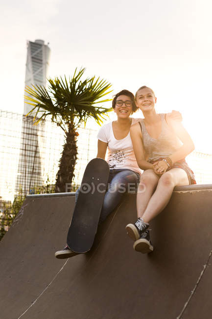 Friends sitting at edge of skateboard ramp — Stock Photo