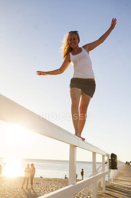 Young woman walking on bridge rail — Stock Photo
