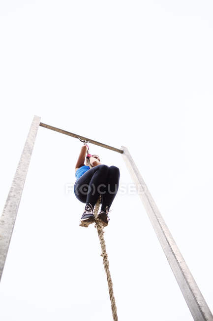 Fit woman climbing rope — Stock Photo