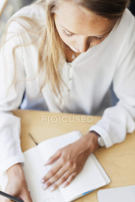 Jeune femme écrivant dans le livre — Photo de stock