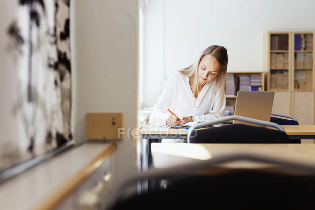 Mujer joven escribiendo en libro - foto de stock