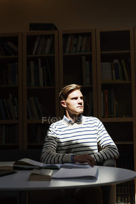 Продуманий студент сидить у бібліотеці — стокове фото