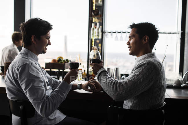 Jeune couple gay assis au bar — Photo de stock