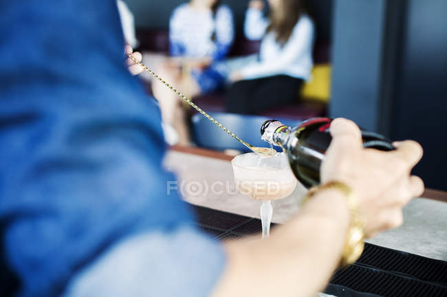 Bartender pouring cocktail in glass — Stock Photo