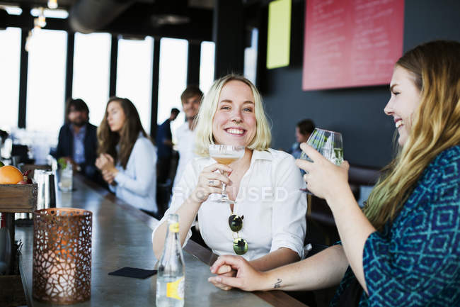 Pareja lesbiana cogida de la mano en el bar - foto de stock