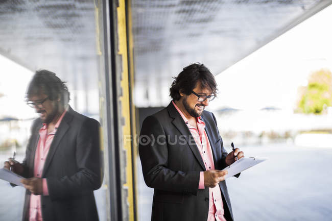 Businessman standing and writing on document — Stock Photo