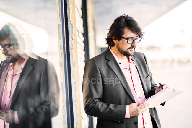 Geschäftsmann steht und schreibt auf Dokument — Stockfoto