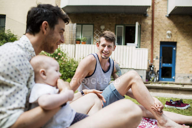 Gay pareja jugando con bebé chica - foto de stock