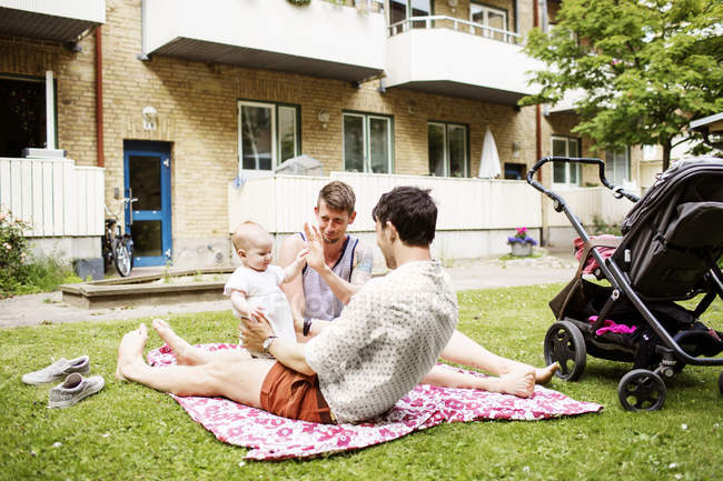 Gay couple playing with baby girl — Stock Photo