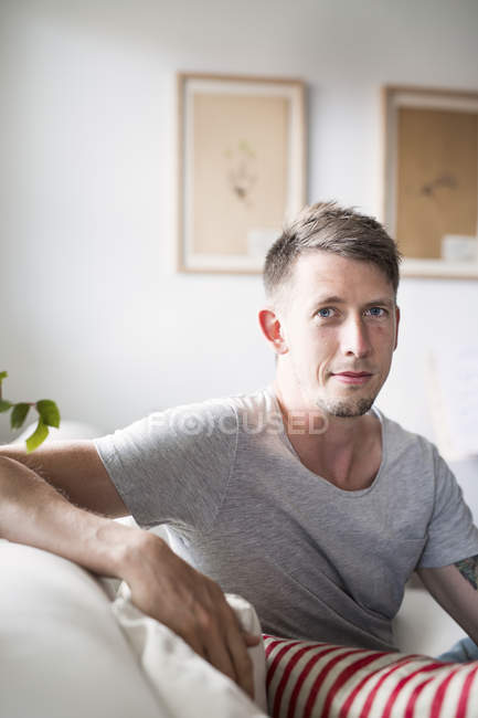 Hombre adulto joven sentado en el sofá - foto de stock