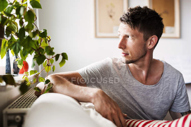 Молодой взрослый мужчина сидит на диване — стоковое фото