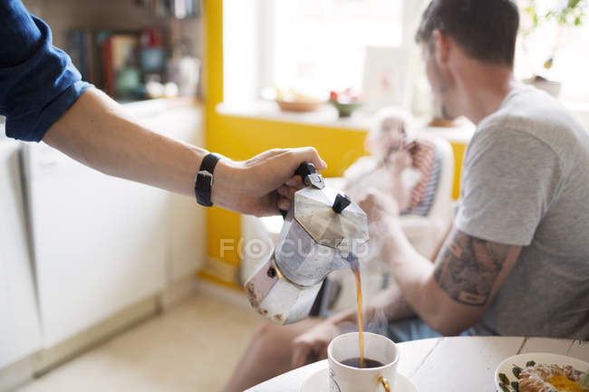 Мужчина наливает кофе в чашку — стоковое фото