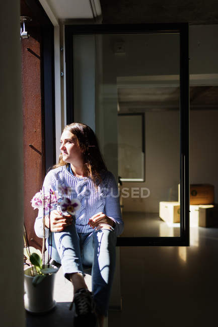 Young woman sitting on window sill — Stock Photo