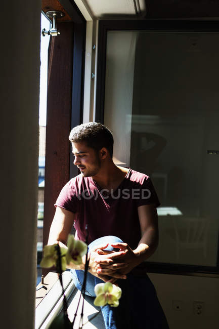 Young man sitting on window sill — Stock Photo