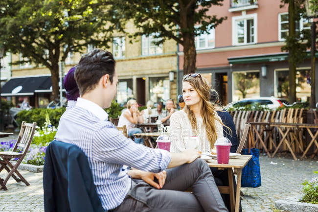 Друзья сидят в кафе на тротуаре — стоковое фото