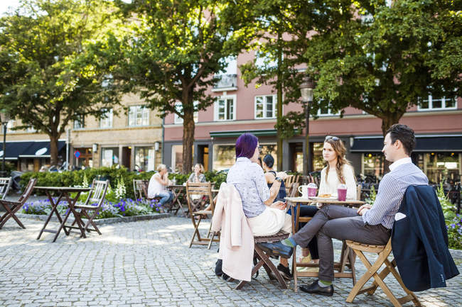Друзья говорят в кафе на тротуаре — стоковое фото