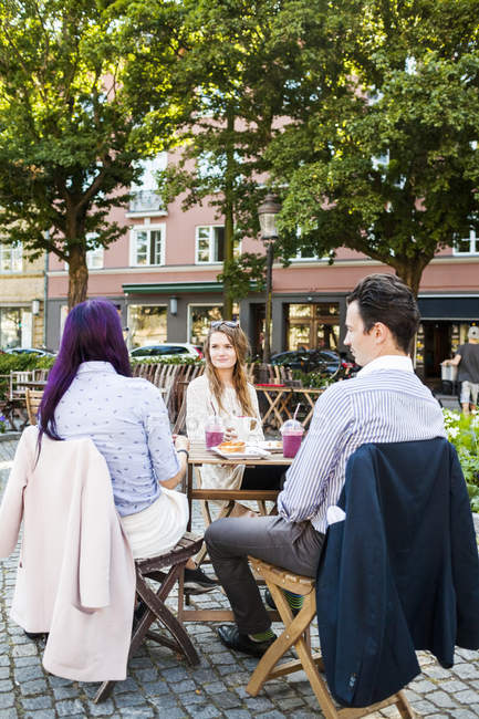 Друзья говорят в кафе на тротуаре — стоковое фото