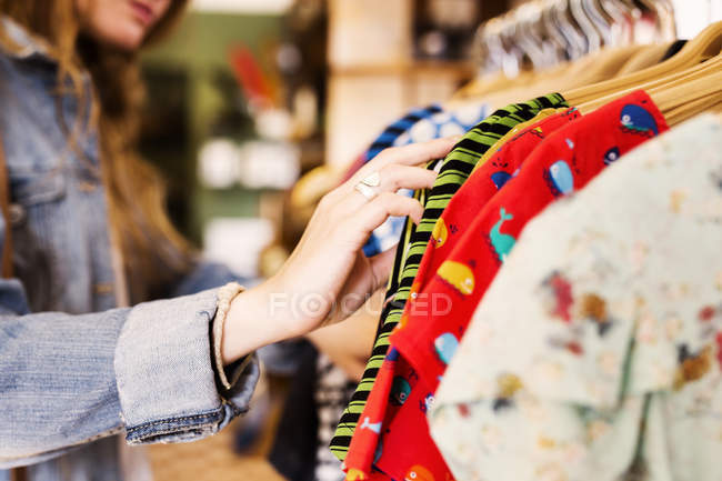 Donna che sceglie i vestiti in negozio — Foto stock