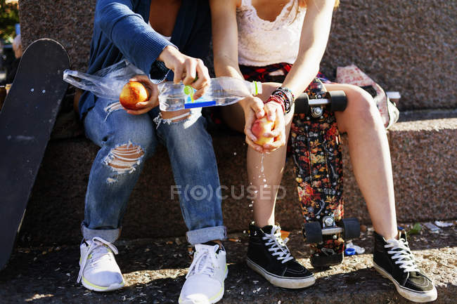 Girls washing apple on street — Stock Photo