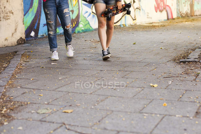 Meninas segurando skates e caminhando — Fotografia de Stock