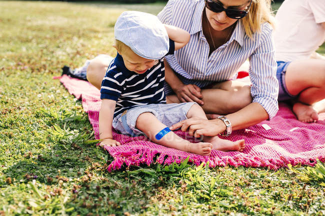 Mãe colocando bandagem na perna do filho — Fotografia de Stock
