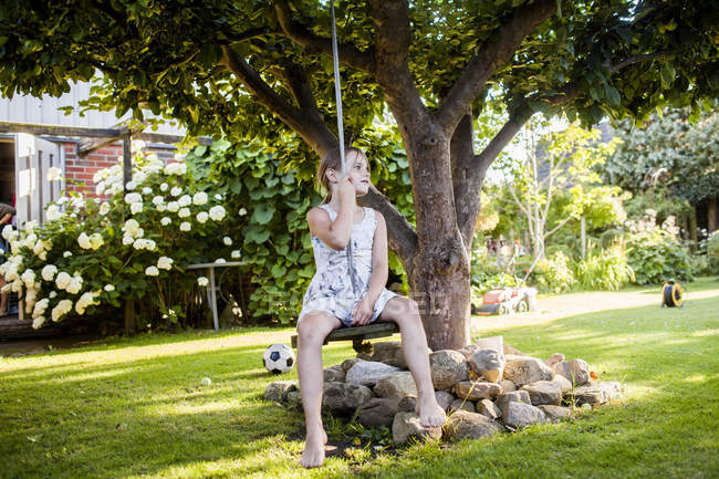 Девушка сидит на качелях в саду — стоковое фото