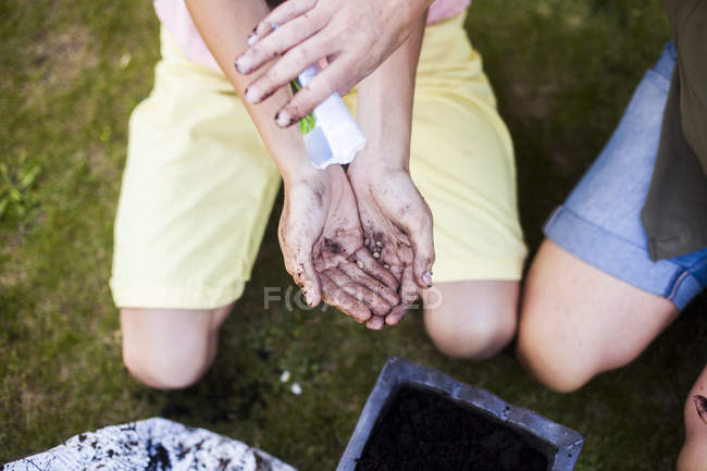 Madre vertiendo semillas en las manos del hijo - foto de stock