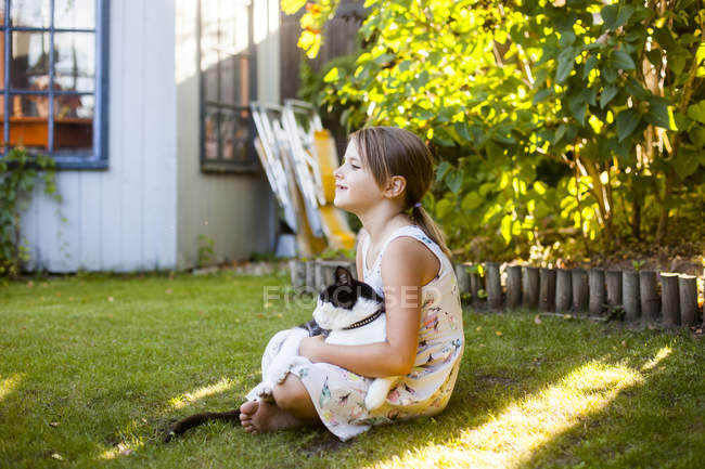 Girl playing with cat in backyard — Stock Photo