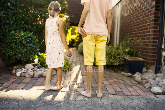 Irmão e irmã de pé no jardim — Fotografia de Stock
