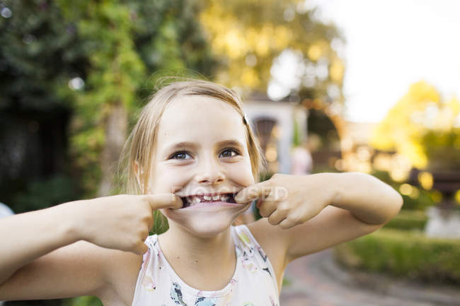 Mädchen zieht Gesichter im Garten — Stockfoto