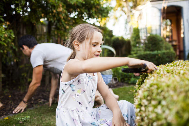 Girl pruning plant with father — Stock Photo