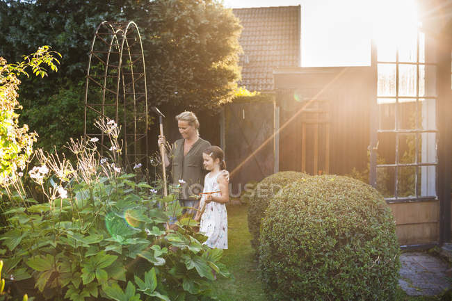 Madre e hija de pie en el patio trasero - foto de stock