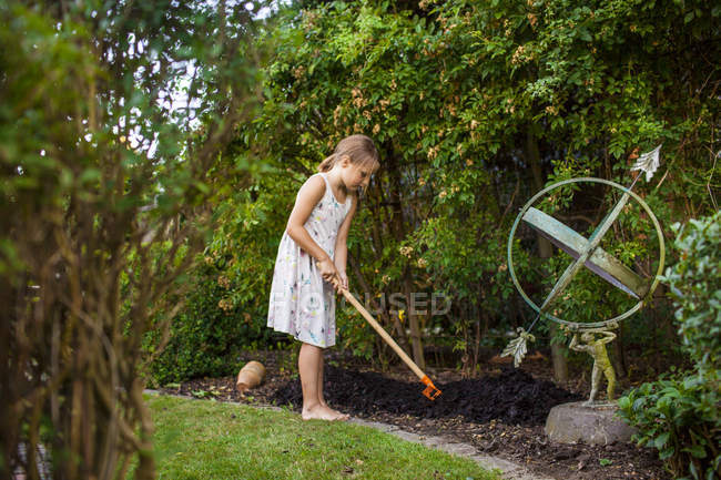 Mädchen streut Dünger mit Gartengabel aus — Stockfoto