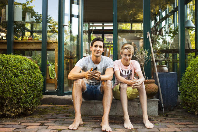 Vater und Sohn sitzen vor Haus — Stockfoto
