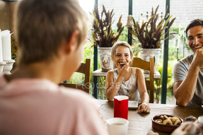 Girl having cookie at family breakfast — Stock Photo