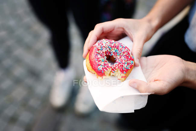 Femme tenant donut dans la rue — Photo de stock