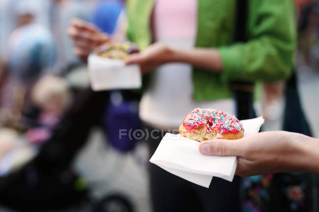 Femme tenant donut dans la rue — Photo de stock