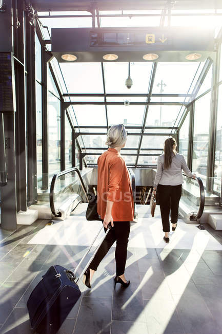 Geschäftsfrauen laufen auf Rolltreppe zu — Stockfoto