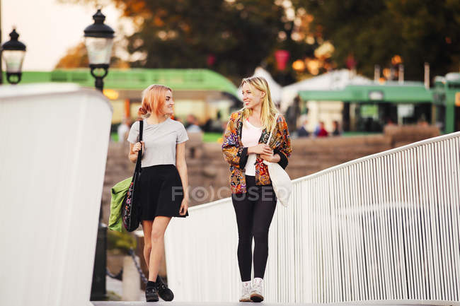 Young women walking on bridge — Stock Photo