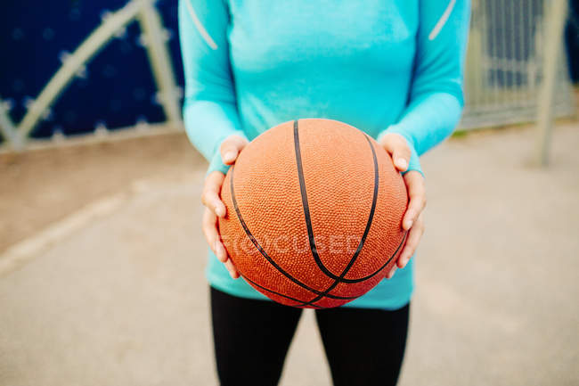 Mulher desportiva segurando basquete — Fotografia de Stock