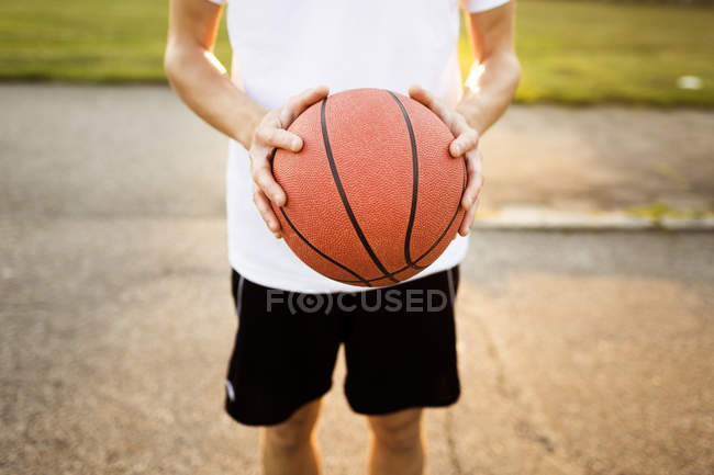 Мальчик проводит баскетбол в парке — стоковое фото