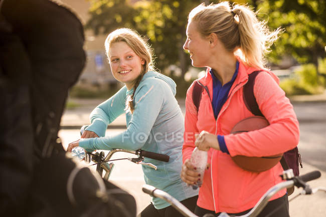 Amigos femininos em pé de bicicleta — Fotografia de Stock