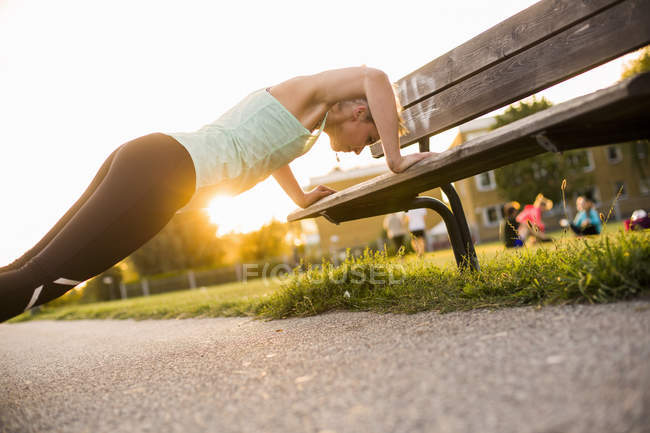 Chica haciendo flexiones en el banco - foto de stock