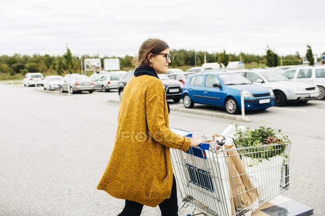 Giovane donna spingendo carrello della spesa — Foto stock