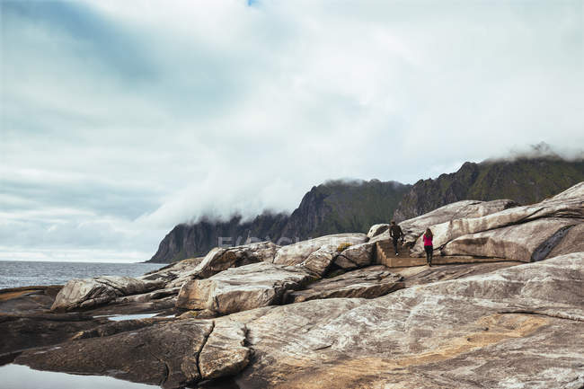 Hombre y mujer caminando sobre rocas - foto de stock