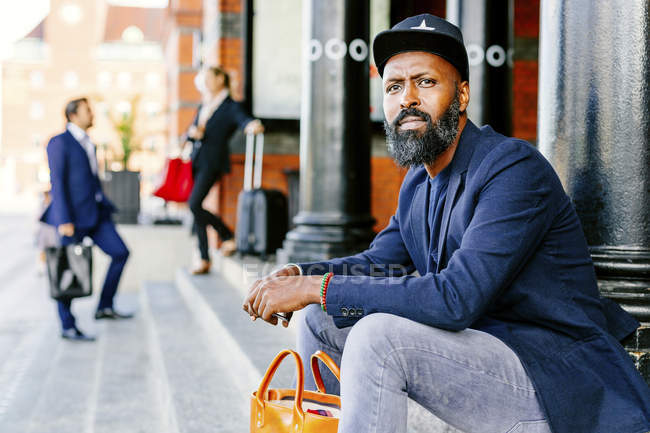 Hombre seguro sentado en los escalones - foto de stock