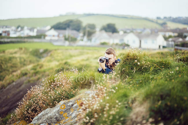 Hombre fotografiando en colina cubierta de hierba - foto de stock