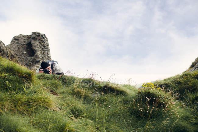 Homme photographiant sur une colline herbeuse — Photo de stock