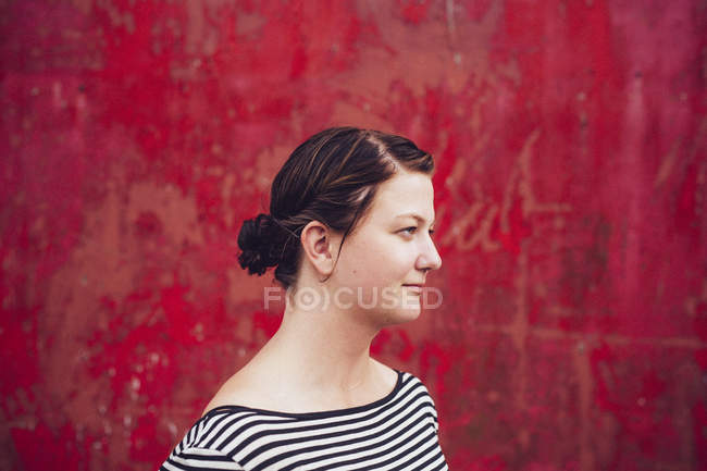 Mujer de pie contra pared roja - foto de stock