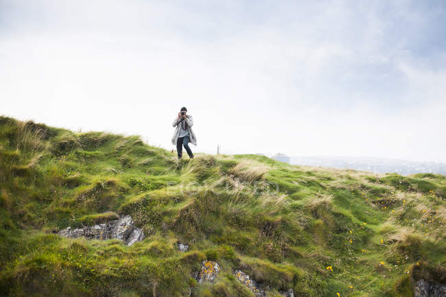 Homem fotografando em colina gramada — Fotografia de Stock